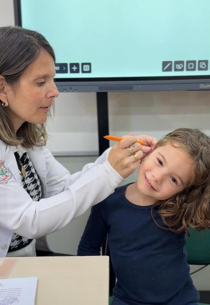 Paola Pittaluga, acupunturista, fazendo aplicação em aluna da EMEF Caetano Peluso.